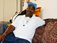 Lonnie M. proudly sits upon the sofa he purchased after coming to Travis Street in September 2014.